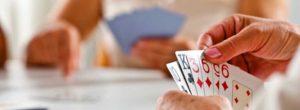 Focus on senior woman's hand holding cards during cards game.